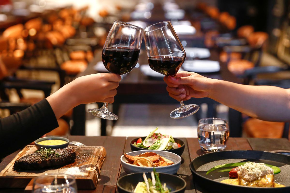 cena de una pareja brindando con copas de vino tinto